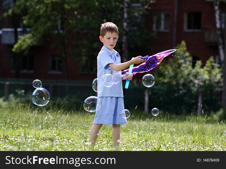 Boy is played with soap bubbles in the street