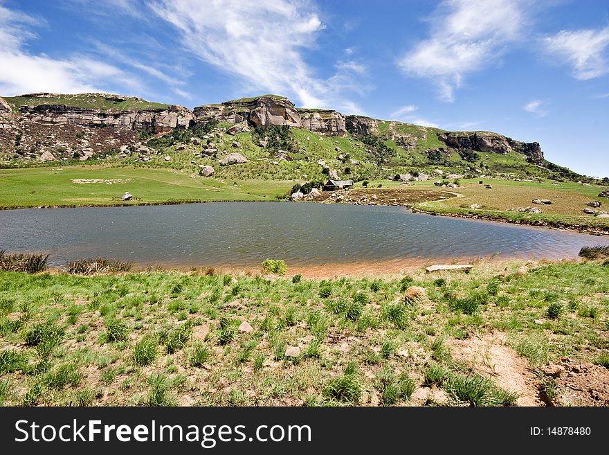 Mountain cottage in green grass at edge of dam