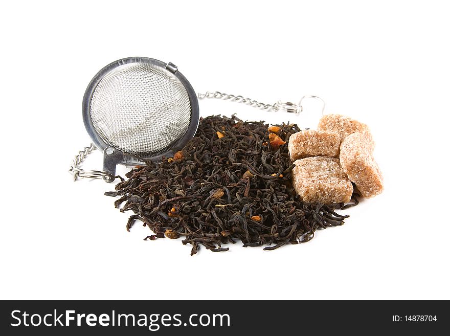 Metallic tea-stainer with a heap of dry tea leaves and four pieces of brown sugar isolated on white. Metallic tea-stainer with a heap of dry tea leaves and four pieces of brown sugar isolated on white