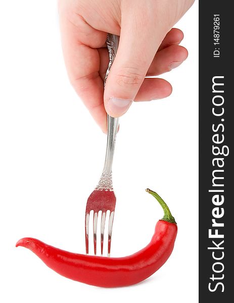 Chili peper in fork with hand isolated