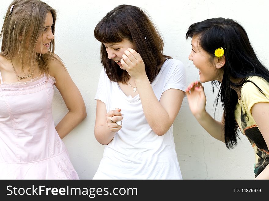 Three female friends standing in front of a white wall