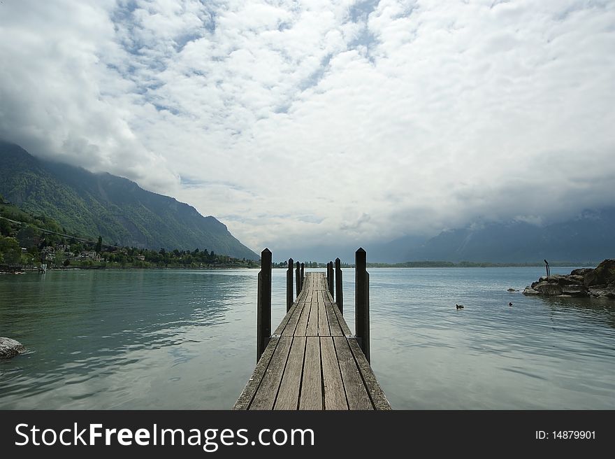 The wooden pier for boats and yachts on the background of the lake water and overcast skies