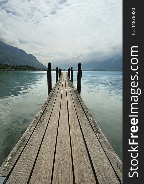 The wooden pier for boats and yachts on the background of the lake water and overcast skies