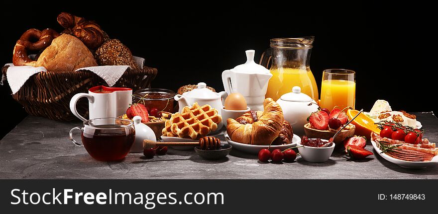 Huge healthy breakfast on table with coffee, orange juice, fruits, waffles and croissants. Good morning concept