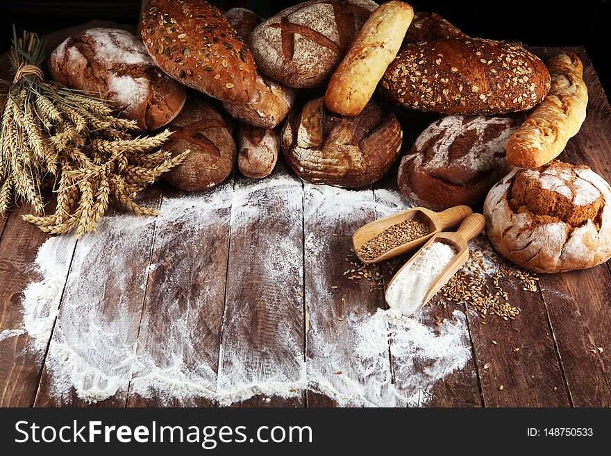 Different kinds of bread and bread rolls on board from above. Kitchen or bakery