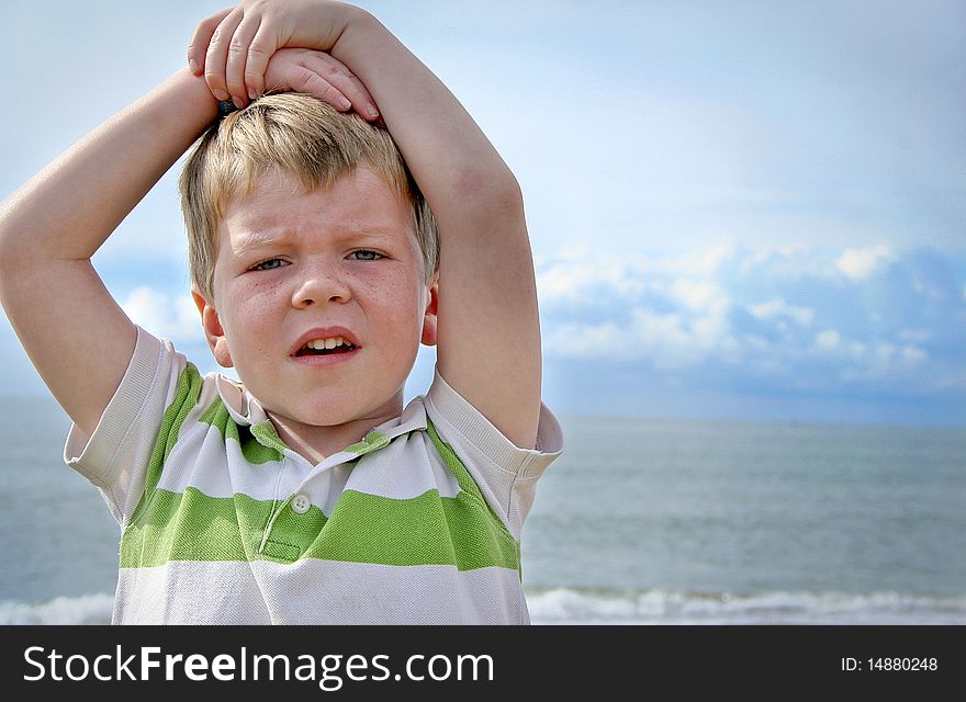A young boy at the sea side, with his arms on his head looking into the camera. A young boy at the sea side, with his arms on his head looking into the camera.