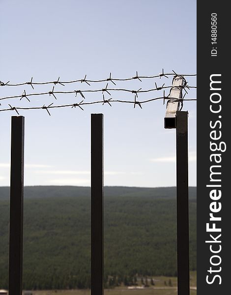 Fence with a barbed wire on a background of blue sky