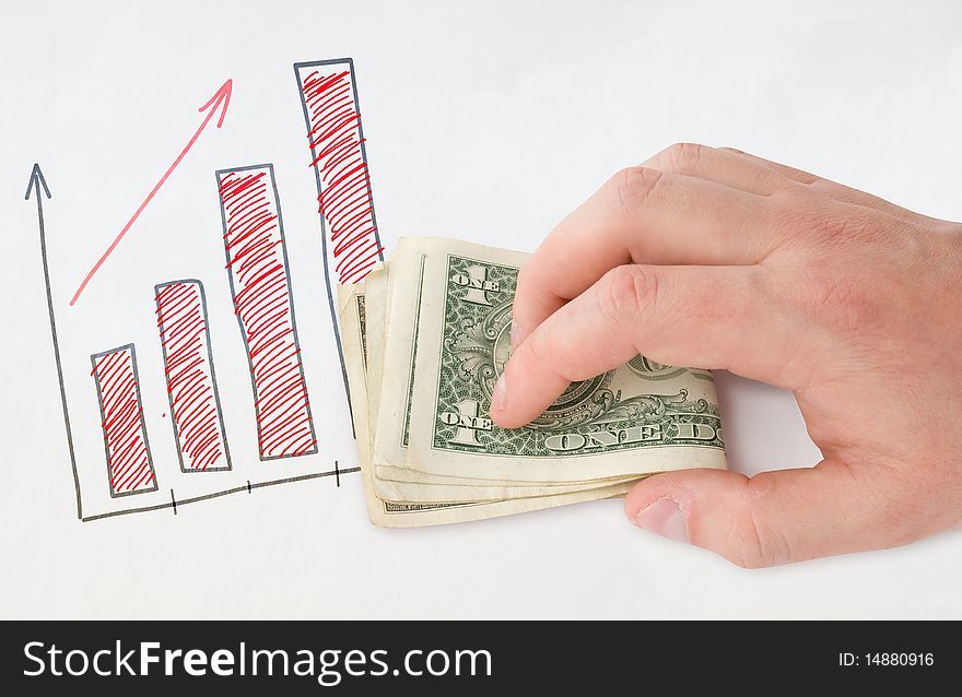 Holding money in hand near drawing graph over white paper