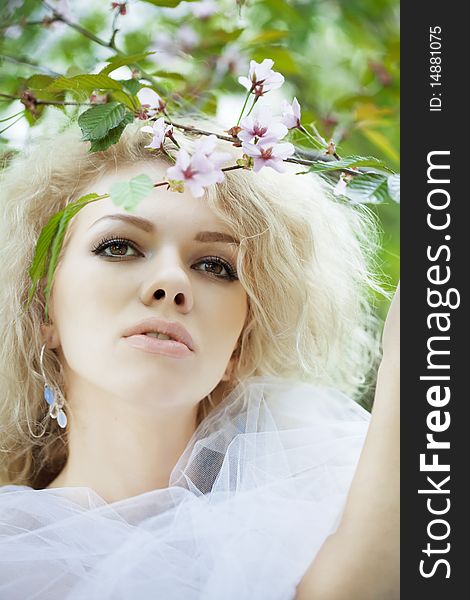 The image of a beautiful positive girl in a park, surrounded by flowers