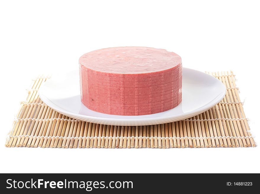 Sausage with fat impregnations is cut by slices and placed on a white plate. Sausage with fat impregnations is cut by slices and placed on a white plate.