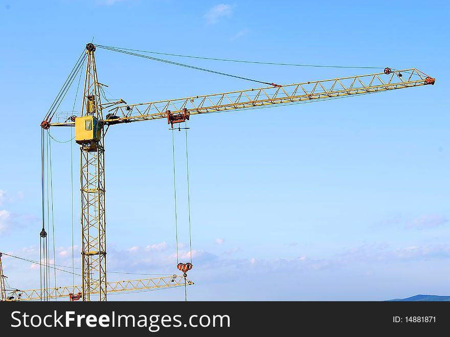 Two building cranes against the blue sky in the summer. Two building cranes against the blue sky in the summer