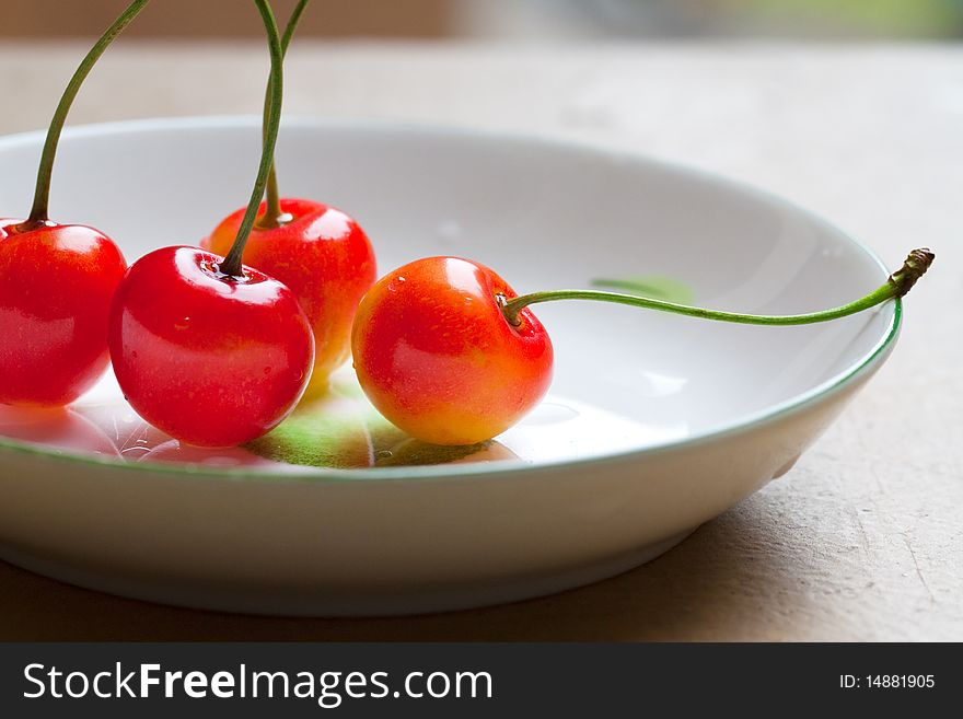 Four red fresh yummy cherry on a dish.