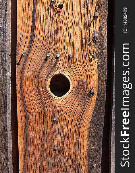 View of a knot hole in a weathered board on the side of building. View of a knot hole in a weathered board on the side of building.