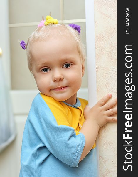 A little boy on the head with hairpins smiles standing near corner of the room. A little boy on the head with hairpins smiles standing near corner of the room