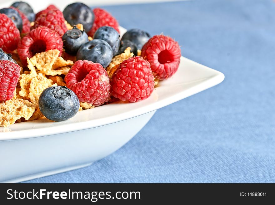 Bowl of berry cereal on blue tablecloth. Shallow depth of field. Bowl of berry cereal on blue tablecloth. Shallow depth of field.