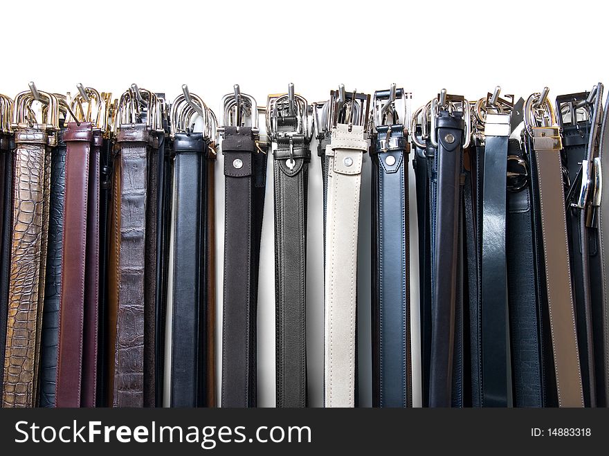 A lot of leather belts in store isolated on white