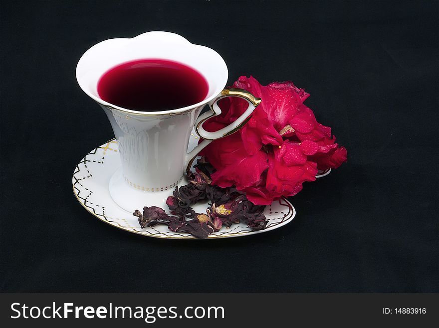 Tea of karkade in a white porcelain cup on a black background. Tea of karkade in a white porcelain cup on a black background