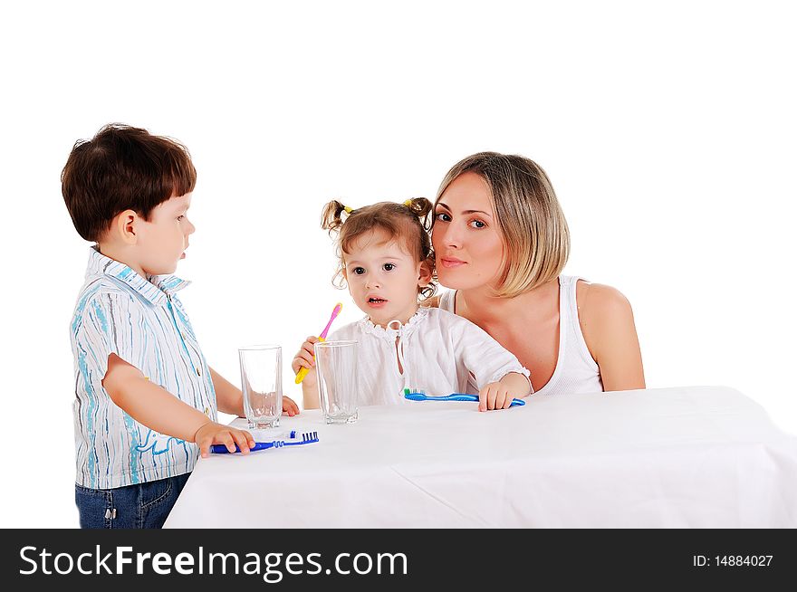 Young mother and her young daughter and son brushing teeth on a white background. Young mother and her young daughter and son brushing teeth on a white background