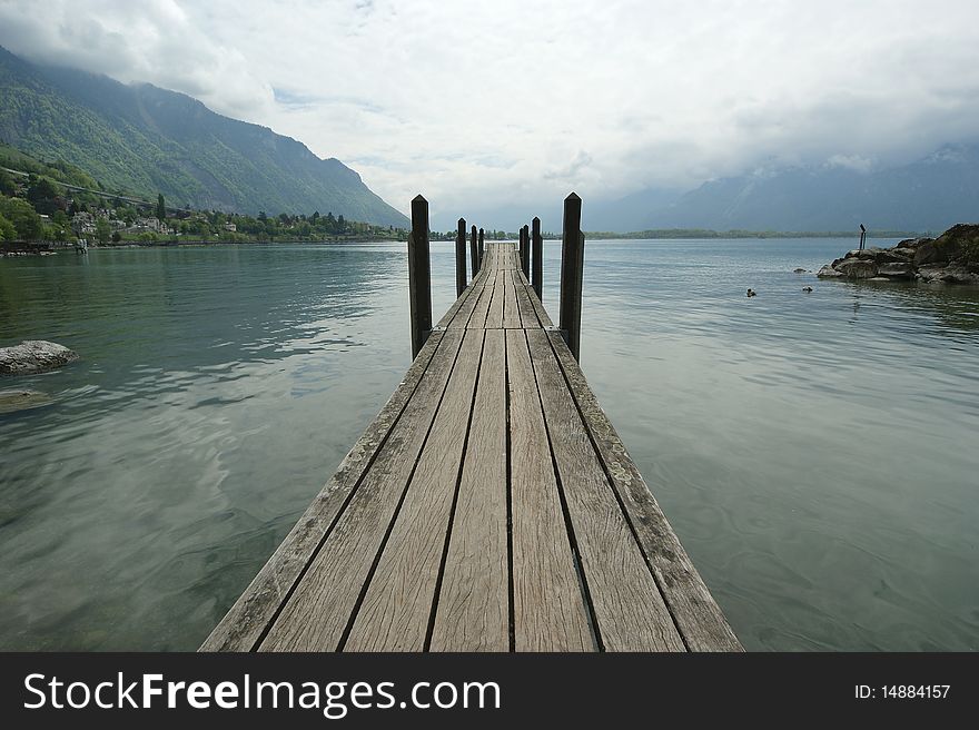 The wooden pier for boats and yachts on the background of the lake water and overcast skies