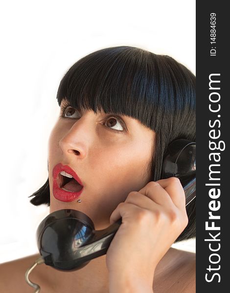 A young woman holds the telephone surprised at what she's listening from the other side, on white background. A young woman holds the telephone surprised at what she's listening from the other side, on white background