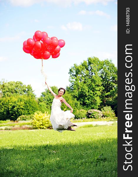 Bride in  white dress with balloons  on  green field. Bride in  white dress with balloons  on  green field