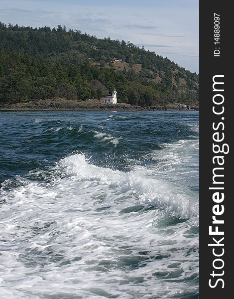 The wake of a boat causes white foam while looking back at the Lime Kiln Lighthouse on the San Juan Islands in Washington state. The wake of a boat causes white foam while looking back at the Lime Kiln Lighthouse on the San Juan Islands in Washington state.