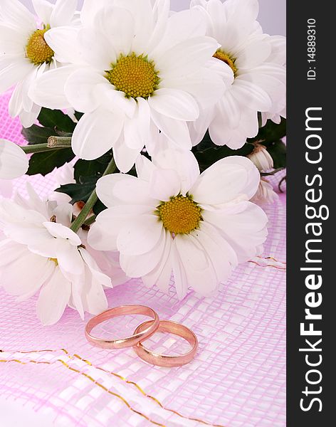 Wedding rings and flowers composition. White petals.