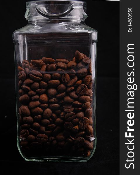 Brown fried grains of coffee scattered on a black background