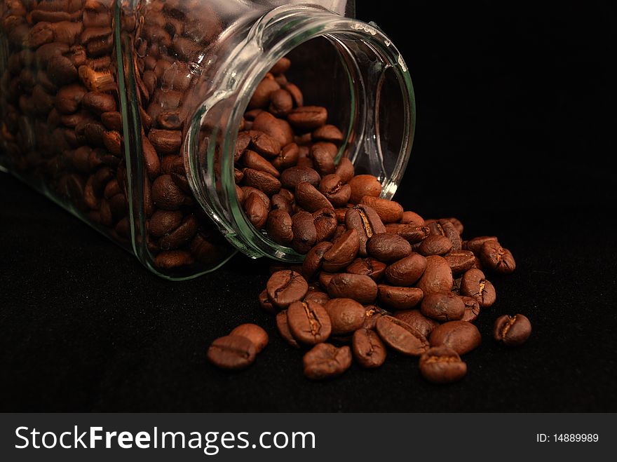Brown fried grains of coffee scattered on a black background