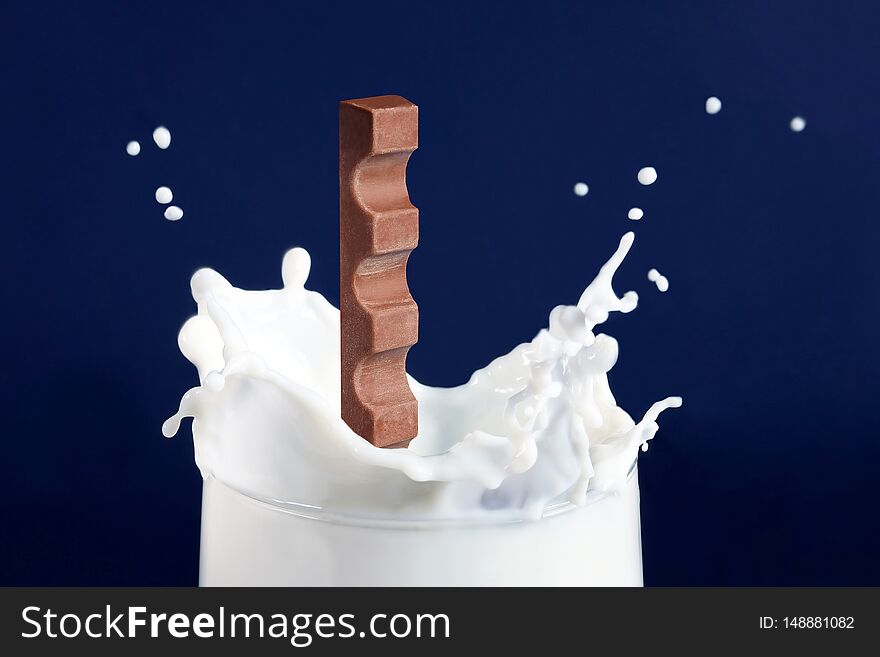 Chocolate falling into milk on blue background