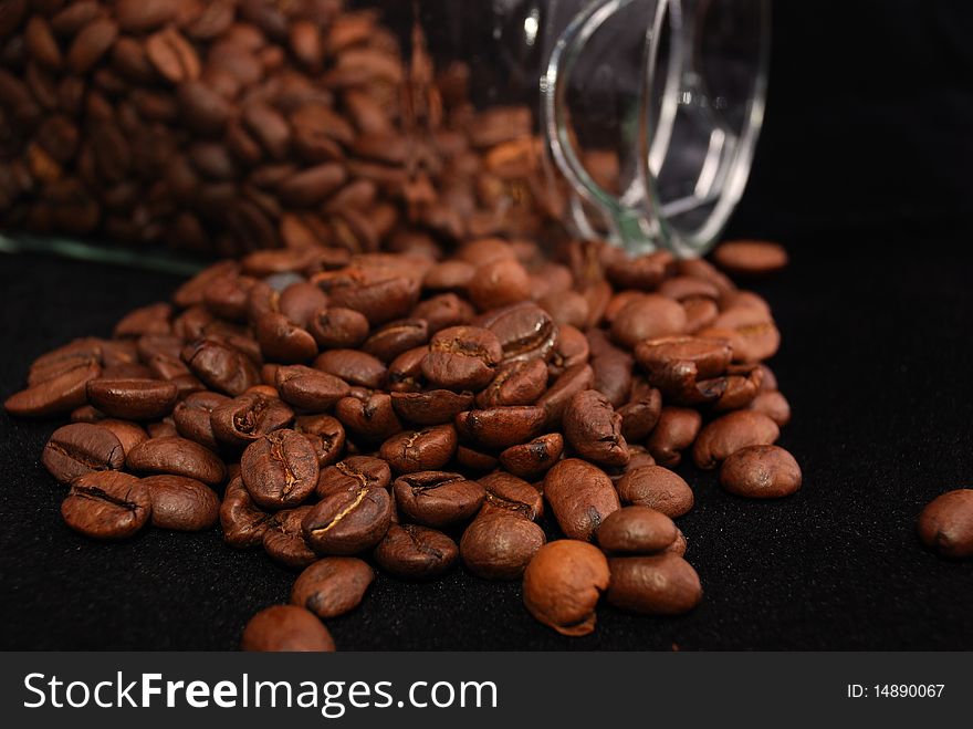 Brown fried grains of coffee scattered on a black background