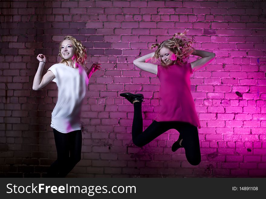 Teenage girl jump in the air against brick wall urban style lit with flash. Teenage girl jump in the air against brick wall urban style lit with flash