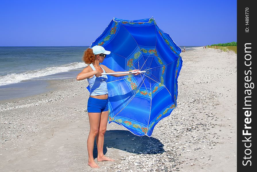 The Woman Opens The Blue Umbrella On The Beach