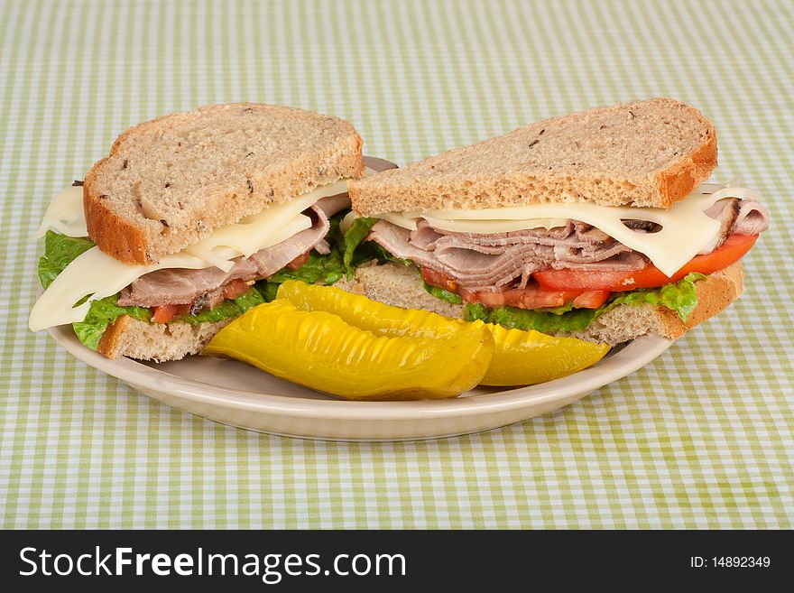 Roast beef sandwich on rye bread with swiss cheese, tomato, lettuce and pickles