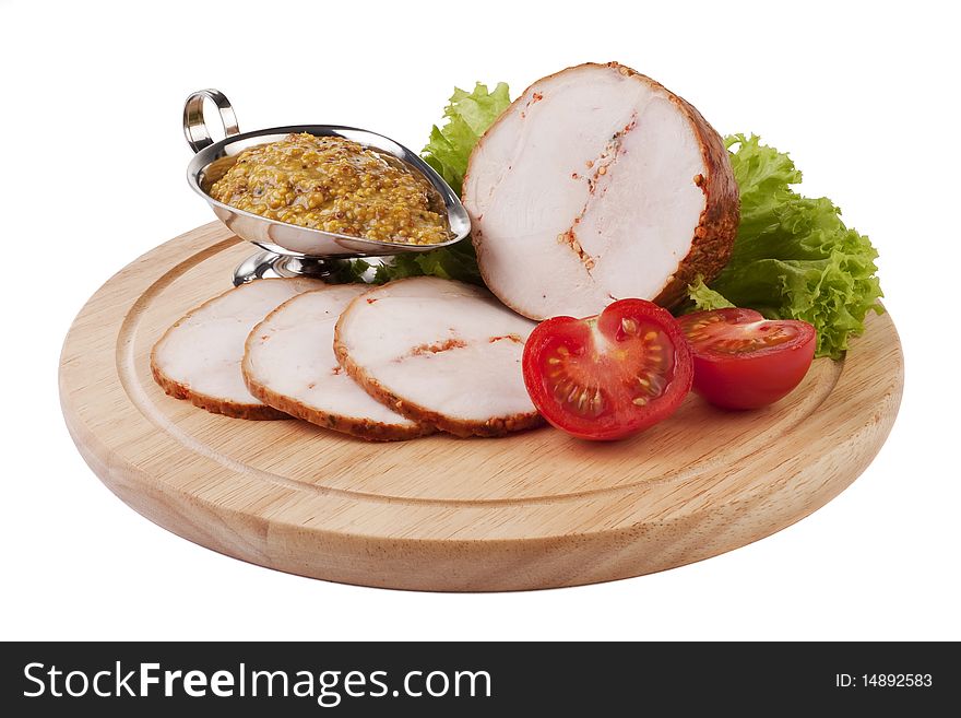 Sliced ham with mustard and vegetables on a wooden plate isolated