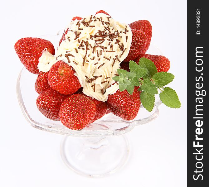 Strawberries in a glass cup with whipped cream, chocolate sprinkles and lemon balm twig. Strawberries in a glass cup with whipped cream, chocolate sprinkles and lemon balm twig