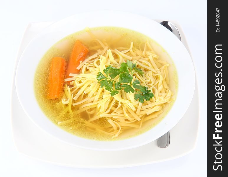 Chicken soup with macaroni and carrots decorated with parsley on a plate with a spoon