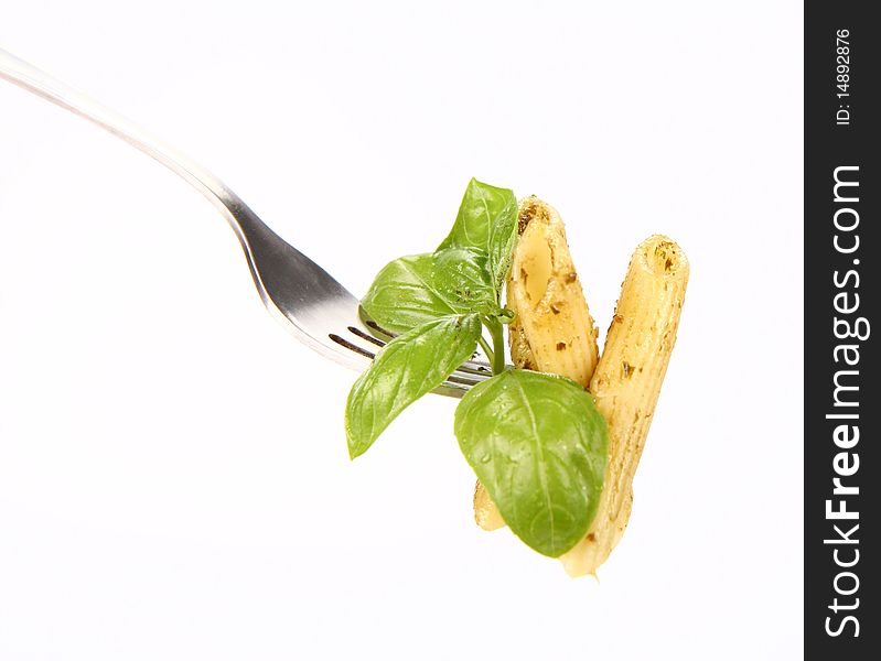 Penne with pesto on a fork decorated with basil