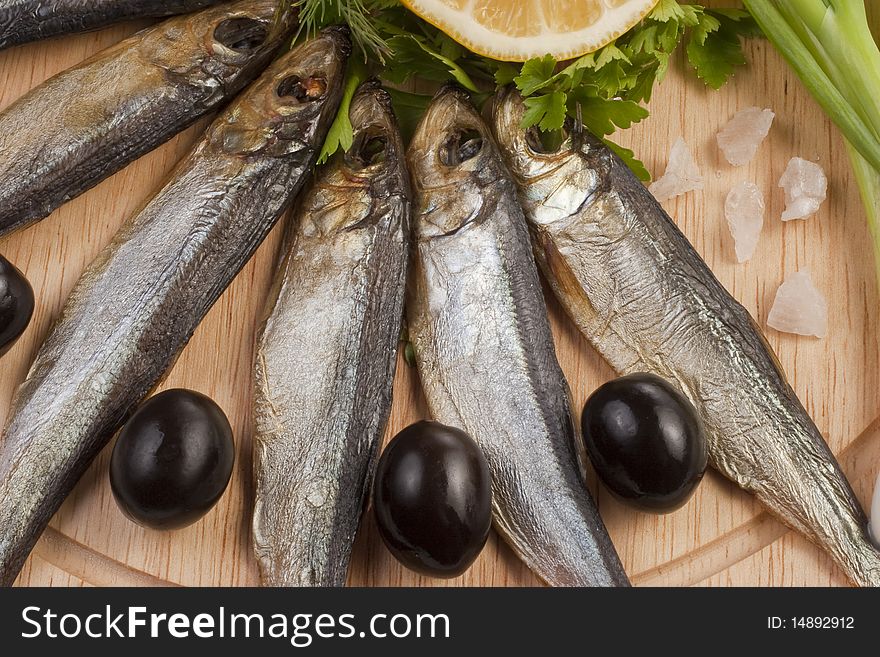 A composition with smoked clupea herring fish (Clupea harengus membras) on wooden plate isolated on white. A composition with smoked clupea herring fish (Clupea harengus membras) on wooden plate isolated on white