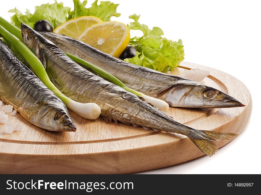 A composition with smoked saira fish (cololabis saira) on wooden plate isolated on white. Closeup