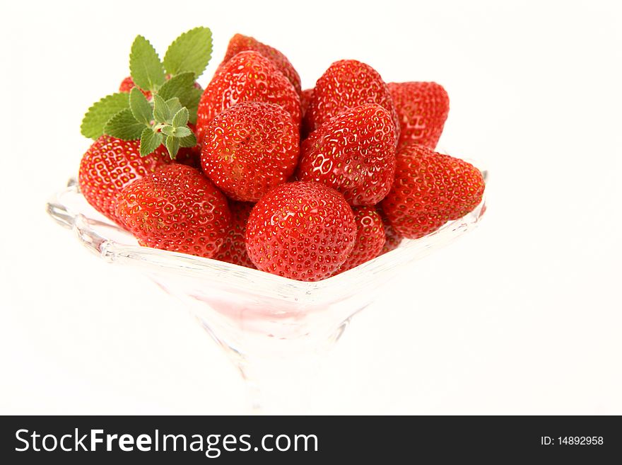 Strawberries in a cup decorated with a lemon balm twig on white background. Strawberries in a cup decorated with a lemon balm twig on white background