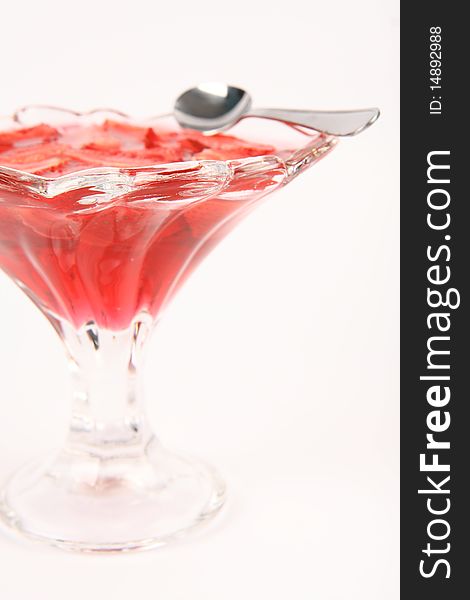 Jelly with strawberries in a glass cup with a spoon