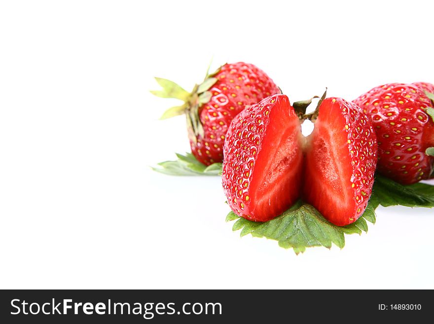 Strawberries on a leaf, one cut in half, on white background, with space for text
