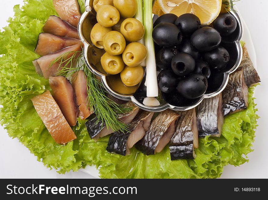 A composition with smoked herring pieces with vegetables on plate isolated on white. Top view closeup