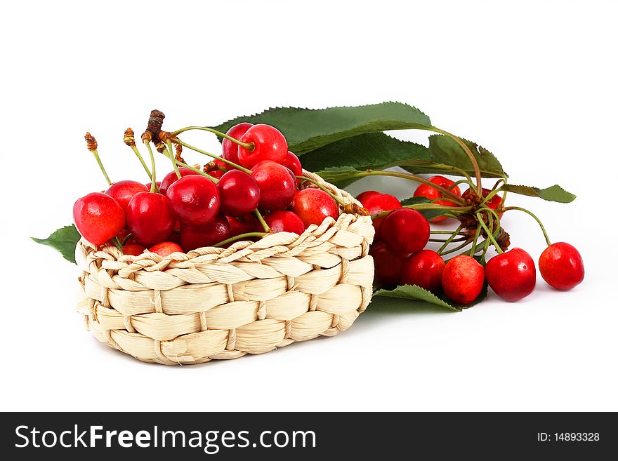 Ripe berries of a sweet cherry in a basket with a branch on a white background