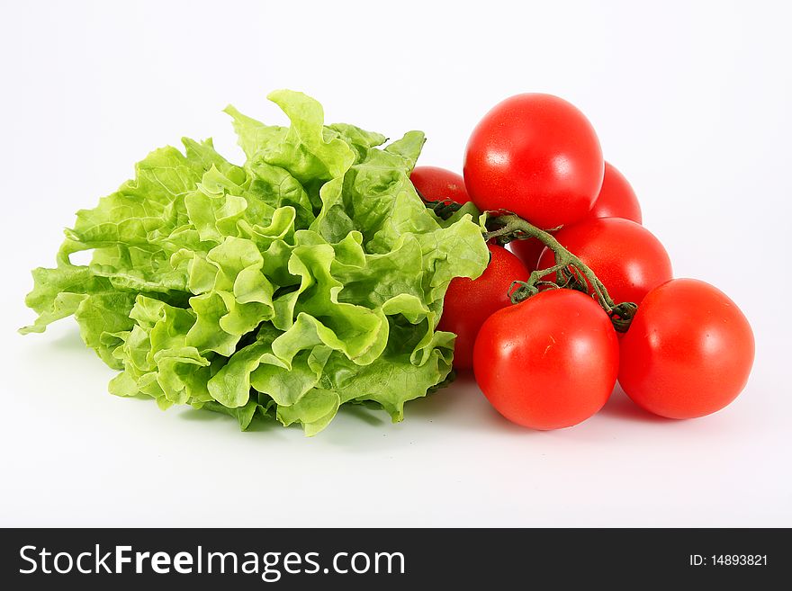 Lettuce green and red tomatoes on an isolated white background. Lettuce green and red tomatoes on an isolated white background