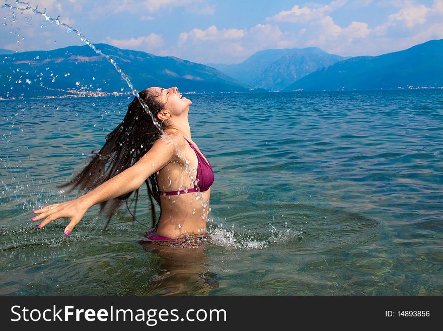 Young, attractive woman, having fun in the water, straying her head back, letting it splash some water. Shot to capture the movement and freeze the action. Young, attractive woman, having fun in the water, straying her head back, letting it splash some water. Shot to capture the movement and freeze the action
