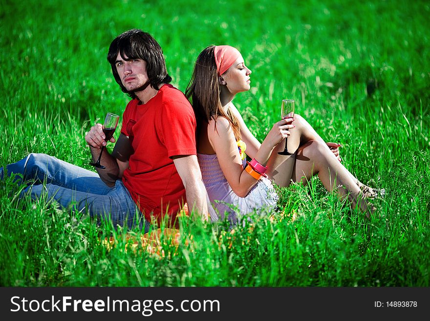 Boy and nice girl with wineglasses on grass