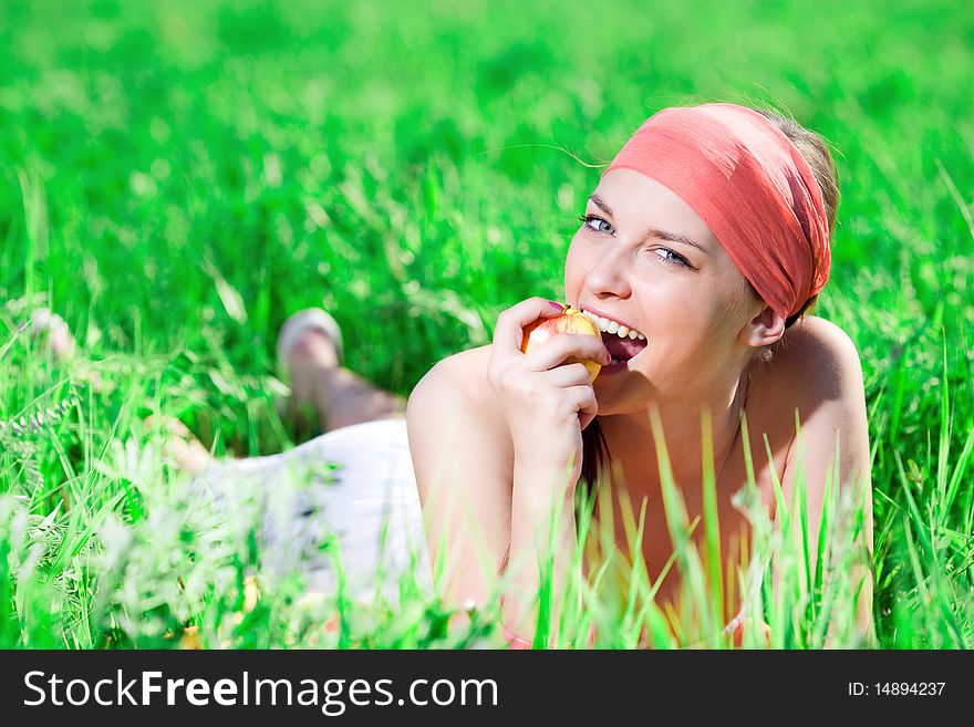 Girl in kerchief with apple on grass. Girl in kerchief with apple on grass