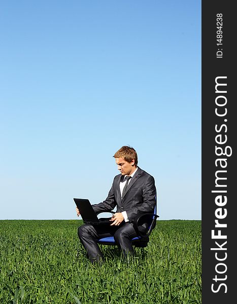 Businessman relaxing on green grassland under blue sky. Businessman relaxing on green grassland under blue sky